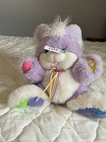 Front view of purple and white plush bunny showing ribbon bow and coloured paw pads