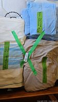 Stack of beige, light blue, and striped sheets with labels indicating sizes and types