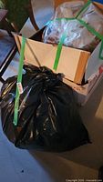 Cardboard box and tied garbage bag containing rags