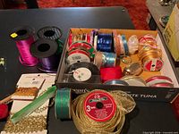 Spools of ribbon, decorative trim packages, green stylus on tabletop
