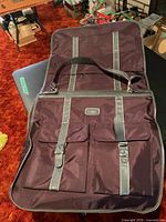 Garment bag opened showing exterior pockets, shoulder strap and overall design