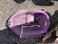 Purple plastic child’s sled showing seat, pull strap and overall wear