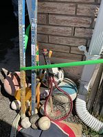 Cluster of hockey sticks, balls and rackets in driveway
