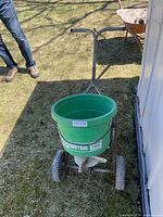 Front three-quarter view of broadcast spreader showing hopper, wheels, handle
