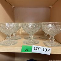 Front view of six clear stemmed dessert bowls on shelf