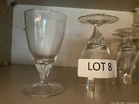 Four clear stemmed glasses, one upright and three inverted, showing twisted stems and footed bases