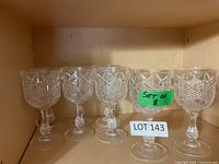 Set of 8 clear pressed glass wine goblets on shelf