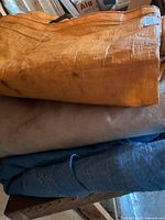 Stacked orange tarp over beige cloth and blue tarp