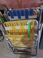 Stacked view of two webbed folding chairs and chaise loungers showing aluminum frames and webbing colors