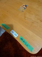 Top view of wooden kids table showing worn spot and tape with measurements
