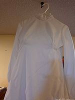 Front view of vintage white wedding dress hanging on hanger