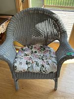 Front view of grey wicker armchair with floral cushion