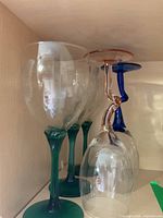 Two green-stem glasses and two upside-down glasses with rose and blue twisted stems