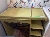 Olive green wooden desk showing top, shelves and drawer