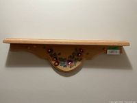 Front view of wood shelf showing floral motif and overall design