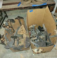Two boxes containing numerous cast iron ice breakers with straps