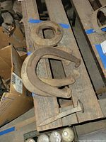 Group shot showing two horseshoes, spike, and pulley collar on wood shelf