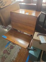 Angled view of desk showing fold-down seat and wood grain