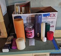 Overall view of assorted candles on countertop and in Xerox box