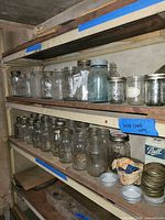 Shelves filled with assorted Ball and unbranded canning jars with lids and rings