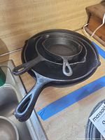 Stacked view of three of the four skillets showing relative sizes and handles