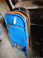 Stacked folding chairs showing blue and orange fronts
