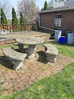 Full view of concrete table with three benches on brick patio