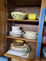 Overall cabinet view showing Pyrex bowl, refrigerator dish, stacks of plates and bowls, wood ring, glass baking dish