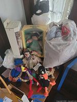 Overall lot view showing boxed Cabbage Patch Kid, boxed porcelain doll, bag of plush, books and other toys