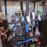 Full shelving unit showing mix of figurines, birdhouses, tins and birdcage