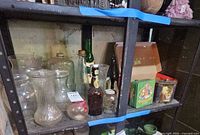 Overview of shelf with glassware, bottles, tins and boxes