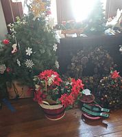 Group shot showing small artificial tree, poinsettia bucket, pinecone wreath, cone tree with lights, and tree stand parts