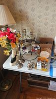 Overview showing candlesticks, cake decorator box, boot vase with flowers and accessories