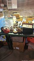 Overview of lot on table showing teapot, utensils, rack, baskets, pegboard and other items