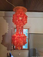 Full view of orange shell disc chandelier hanging from ceiling
