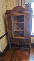 Front view of china cabinet displaying glass door, drawer and decorative veneer panels