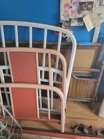 Painted metal headboard and footboard with salmon panels beside faux wood grain frame