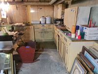 Wide view of multiple yellow metal cabinets with green countertop in basement