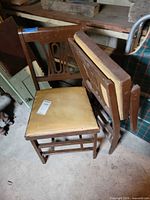 Two brown wood dining chairs with gold vinyl seats shown together
