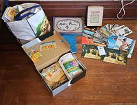 Tote bag, shoebox and loose stacks of postcards, booklets, slide mailer visible on floor