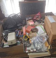 Full view of lot in cardboard box with desk organizers, tape, assorted contents