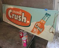 Full view of Orange Crush metal sign and four cans