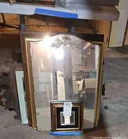 Stack of mirrors showing large over-mantel, light wood mirror, scrollwork frame and square accent mirror