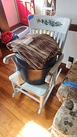 Rocking chair holding stool and folded rugs