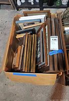 Cardboard box filled with assorted wood and metal picture frames