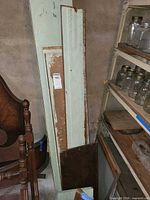 Long light-green boards, brown board and small panels leaning against wall