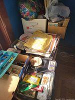 Overall view of mixed sewing supplies on table, including boxes of patterns, trays of notions and scissors