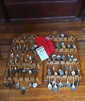 Full lot showing two racks filled with spoons and forks on hardwood floor