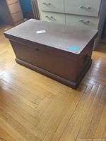 Full view of brown wooden blanket chest on hardwood floor