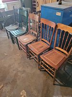Row of five spindle-back dining chairs with varied finishes